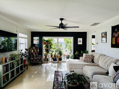 A living room with a fan, couch, and plants.