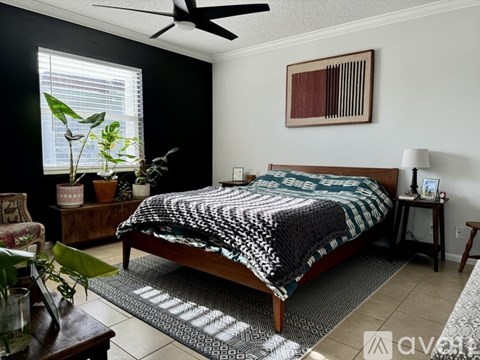 A bedroom with a bed, a chair, and a potted plant.
