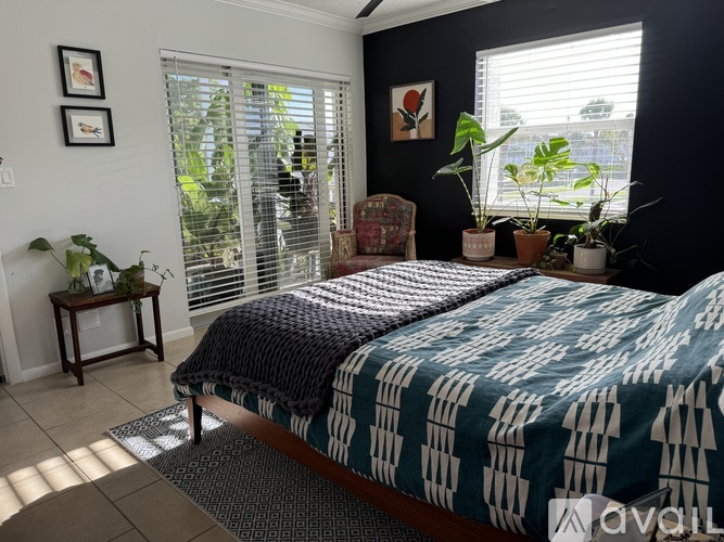 A bedroom with a bed, chair, and potted plants.