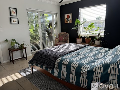 A bedroom with a bed, chair, and potted plants.