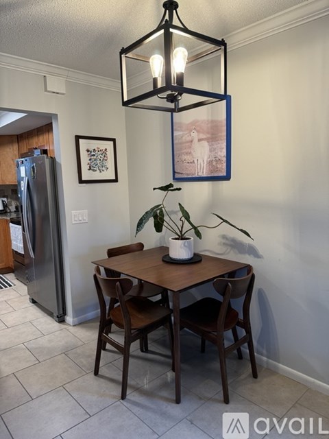 A dining room with a table and chairs and a framed picture on the wall.
