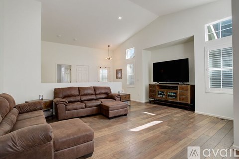 A living room with brown leather furniture and a flat screen TV.
