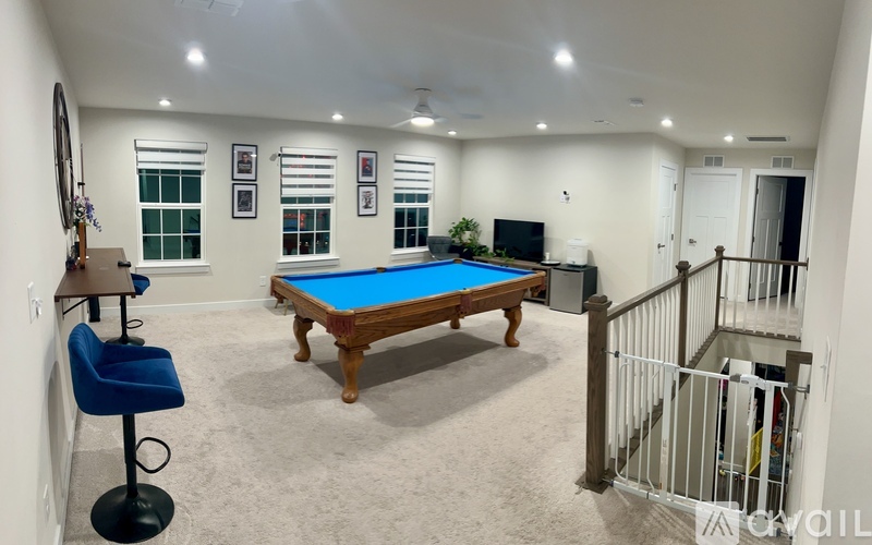 A pool table in a room with a blue chair and a TV.
