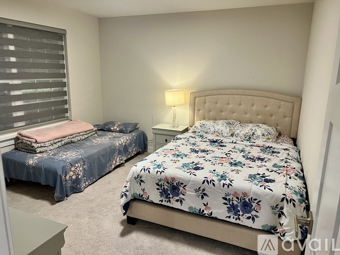 Two beds with floral and solid bedspreads in a bedroom.