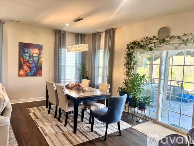 A dining room with a table set for six and a painting on the wall.