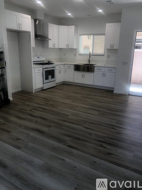A kitchen with white cabinets and a wooden floor.