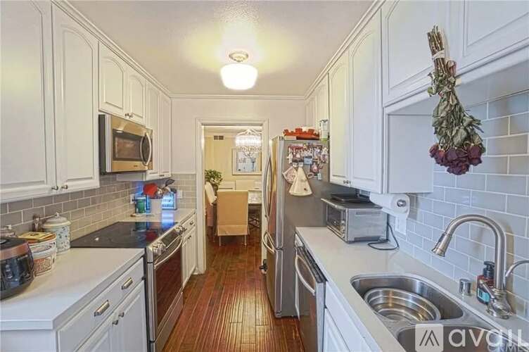 A kitchen with white cabinets and a wooden floor.