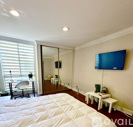 A bedroom with a large bed and a flat screen TV mounted on the wall.