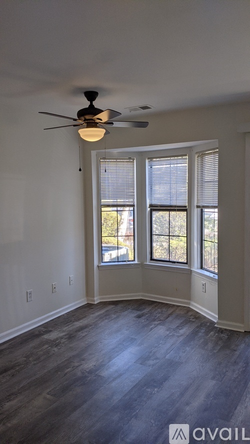 A room with a ceiling fan and a window with blinds.
