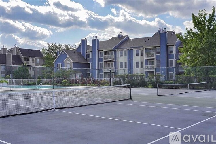 A tennis court is in front of a large blue building.