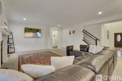 A living room with a large couch and a painting on the wall.