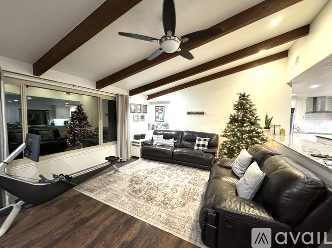 A living room with a black leather couch and a Christmas tree.