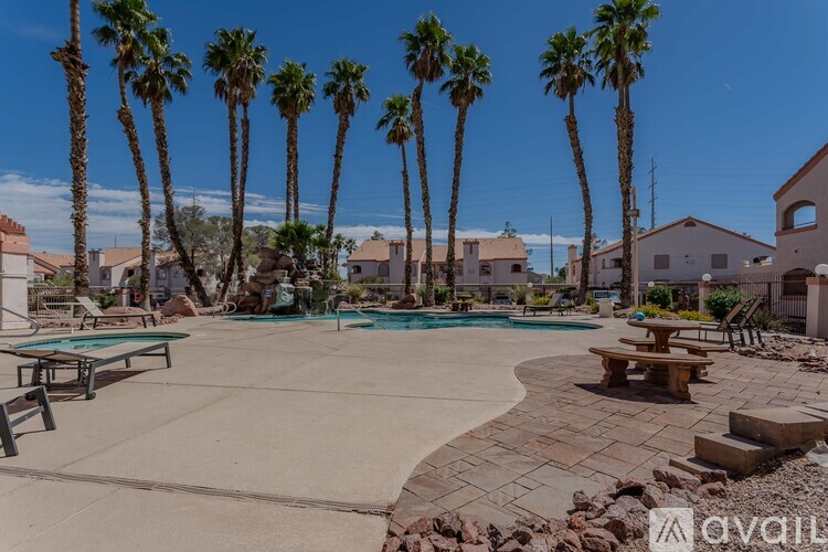 A pool surrounded by palm trees and benches.
