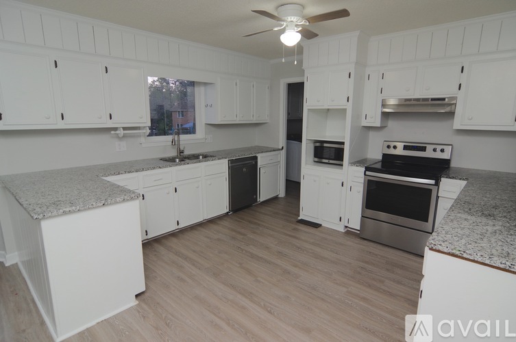 A kitchen with white cabinets and a wooden floor.