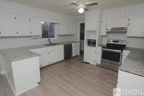 A kitchen with white cabinets and a wooden floor.