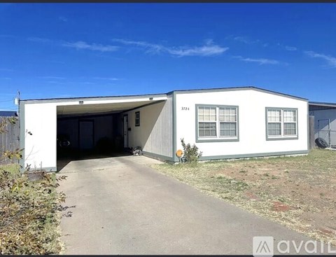A white house with a garage door open and a driveway leading to it.