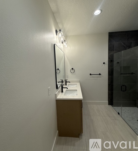 A bathroom with a sink, mirror, and a shower.