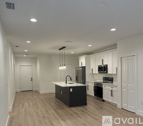 A modern kitchen with a black island and white cabinets.