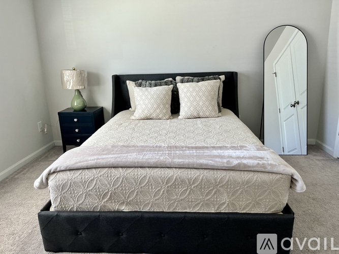 A bed with a white comforter and two pillows sits in a room with a black headboard.