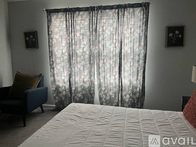 A bedroom with a large bed and a floral curtain.