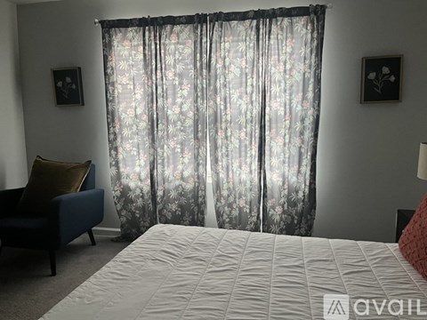 A bedroom with a large bed and a floral curtain.