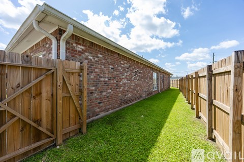 A backyard with a wooden fence and a brick building.
