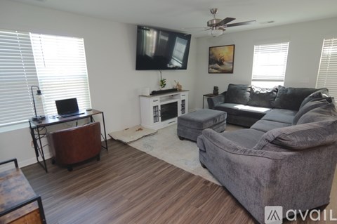 A living room with a grey couch and a television on the wall.