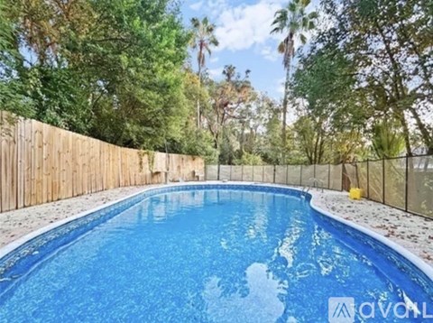 A small in ground pool surrounded by a fence and trees.