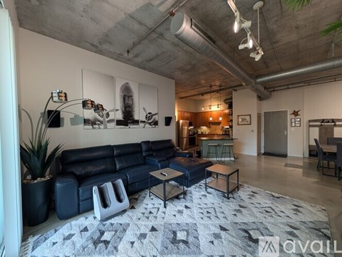 A living room with a dark blue couch and a grey rug.