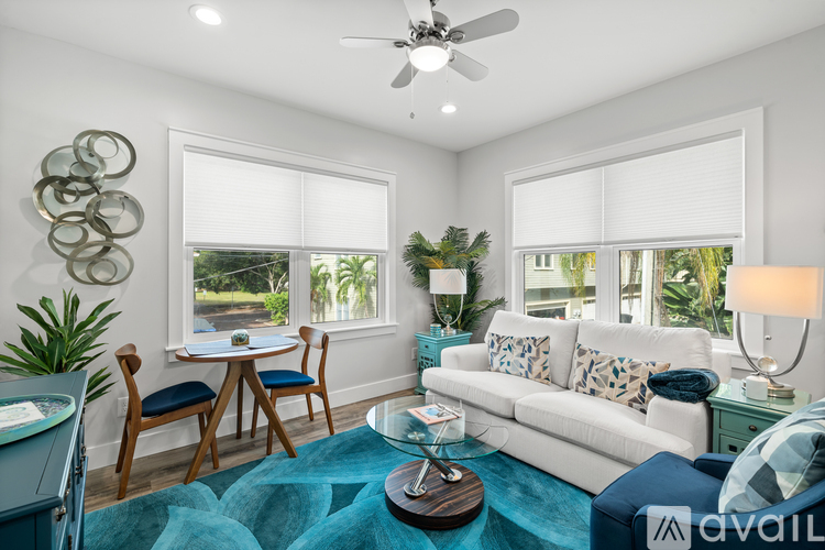 A living room with a white couch, a blue rug, and a ceiling fan.