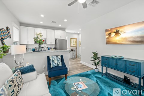 A modern kitchen with a blue chair and a painting of a beach scene on the wall.