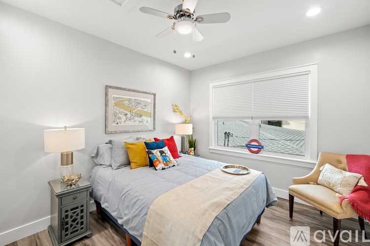 A bedroom with a bed, chair, and ceiling fan.