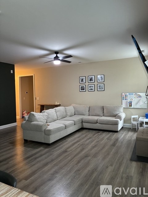 A living room with a grey sectional sofa and a black wall.