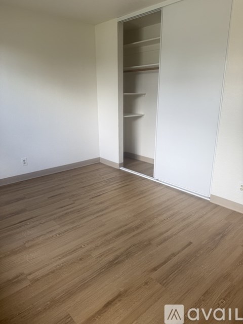 A room with wooden flooring and a white wall with a white closet door.