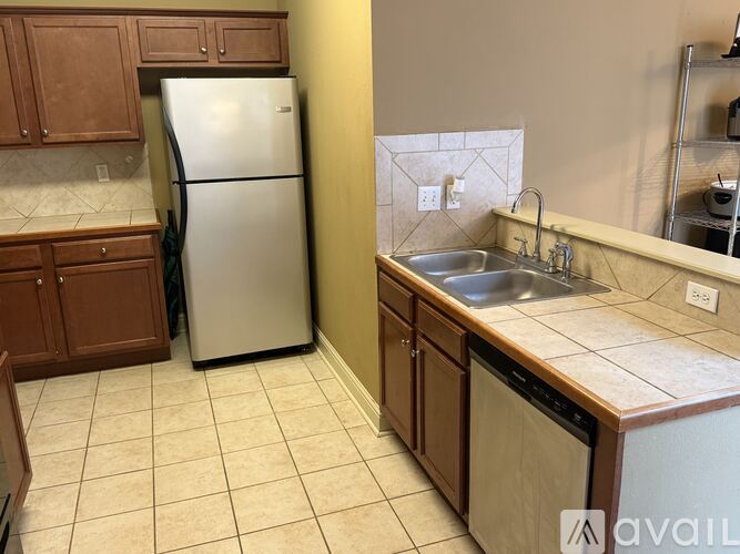 A kitchen with a white refrigerator and a sink with brown cabinets.