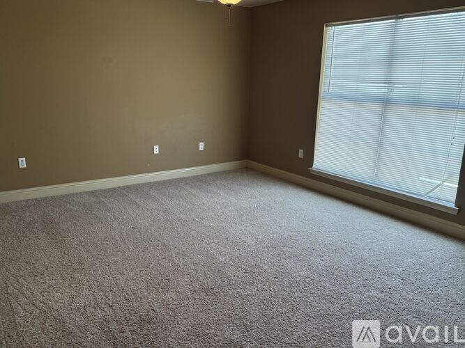 A room with a carpeted floor and a window with blinds.