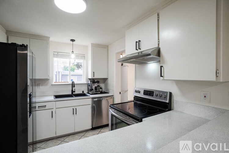 A kitchen with white cabinets and a black refrigerator.