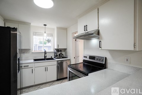 A kitchen with white cabinets and a black refrigerator.