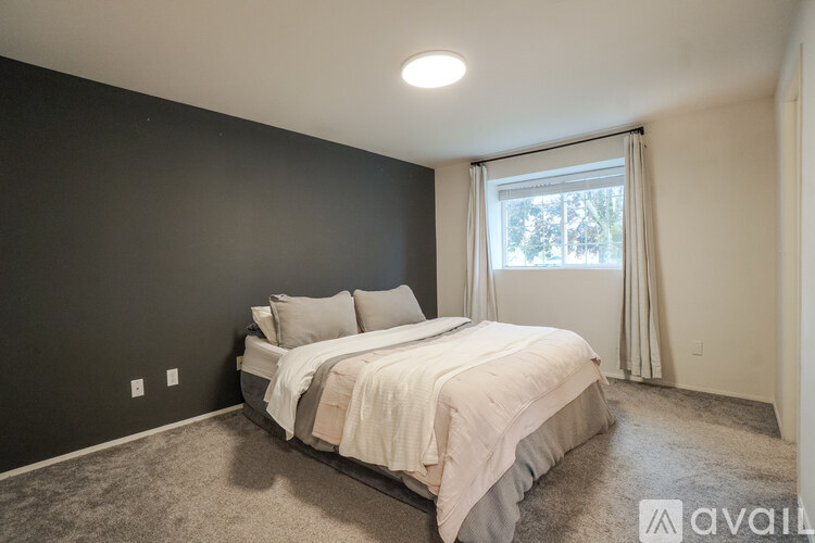 A bedroom with a bed, pillows, and a window with curtains.