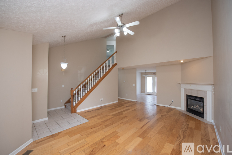 A spacious living room with a fireplace and a staircase.