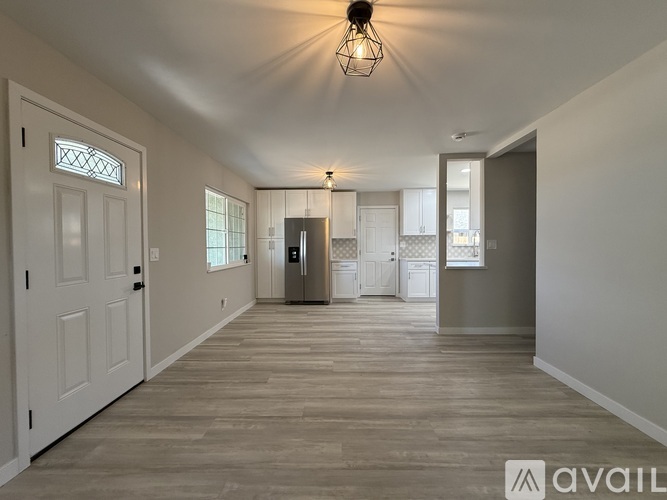 A spacious room with wooden flooring and white walls.