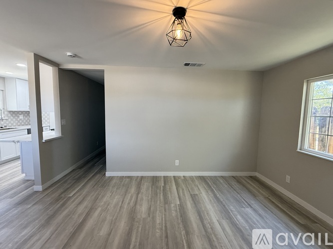 A room with wooden flooring and a window on the right side.