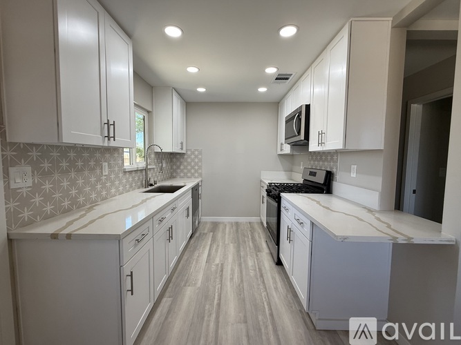 A kitchen with white cabinets and a patterned backsplash.