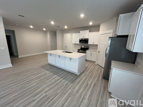 A modern kitchen with white cabinets and a wooden floor.