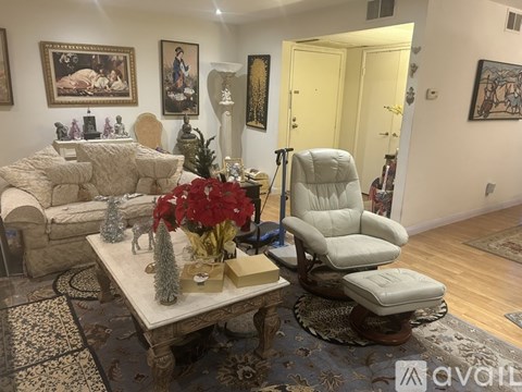 A living room with a white chair and a coffee table with a vase of flowers on it.