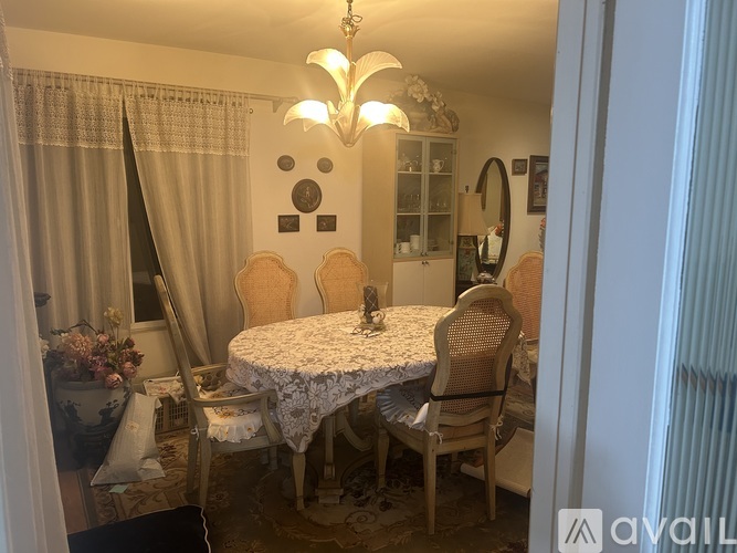 A dining room with a table set for two and a chandelier hanging from the ceiling.