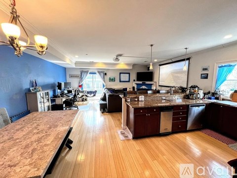 A large open plan kitchen and living room with wooden floors and a long counter.