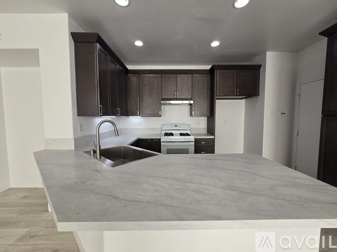 A kitchen with a marble countertop and dark brown cabinets.
