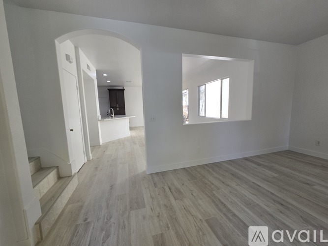 A spacious room with wooden flooring and white walls.