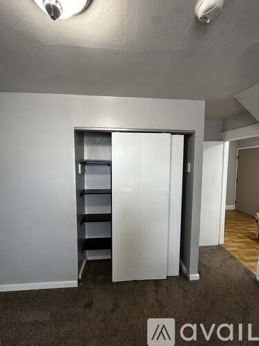 A room with a white wall and a white closet with shelves.